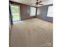 Large bedroom featuring wood paneling, carpet flooring, a ceiling fan, and a door to the exterior at 3412 1St Avenue Nw Cir, Hickory, NC 28601