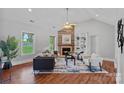 Cozy living room with a fireplace, vaulted ceilings, large windows, and hardwood floors at 7478 Pine Ridge Dr, Denver, NC 28037