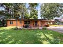 Charming brick home with a cozy outdoor seating area, set amidst a lush green lawn and mature trees at 835 Holshouser Rd, Rockwell, NC 28138