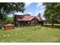 Charming home with a covered porch, landscaped yard and brick well house surrounded by lush greenery and mature trees at 835 Holshouser Rd, Rockwell, NC 28138