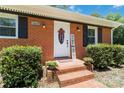 Close-up of the front door with brick steps, black shutters, and potted flowers at 1219 Flowe Dr, Matthews, NC 28104