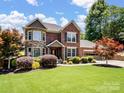 Charming two-story brick and stone home with manicured lawn, colorful trees, and a two-car garage at 165 Cottontail Se Ln, Concord, NC 28025