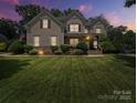 Charming two-story home at dusk with manicured lawn, landscape lighting, and inviting front porch at 1808 Mill Chase Ln, Waxhaw, NC 28173