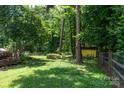 Lush backyard with mature trees, a charming fence, and a yellow storage shed at 2825 Edwin Jones Dr, Charlotte, NC 28269