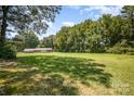 Spacious backyard features a lush lawn and mature trees, with a brick home nestled in the serene landscape at 114 Huffstetler Rd, Gastonia, NC 28056