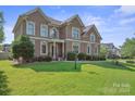 Beautiful brick home featuring a lush green lawn and manicured landscaping at 12004 New Bond Dr, Huntersville, NC 28078