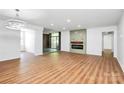Open living room with hardwood floors, stylish light fixture and a sliding glass door to a balcony at 1300 Queens Rd # 405, Charlotte, NC 28207