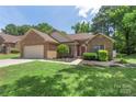 Beautifully landscaped brick home with an attached two car garage, lush lawn, and a cheerful red front door at 14747 Pomerol Ln, Pineville, NC 28134