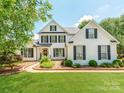 Inviting white brick home with black shutters, a well-maintained lawn, and a welcoming front entrance at 1605 Ambergate Dr, Waxhaw, NC 28173