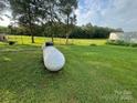 An expansive lawn with a large propane tank and scattered trees in the backyard at 22987 Alonzo Rd, Oakboro, NC 28129