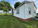 A side view of the home with white siding, brick foundation, and shaded carport at 22987 Alonzo Rd, Oakboro, NC 28129