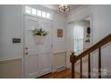 Traditional foyer featuring a hardwood floor, wooden staircase, paneled walls, and a classic white entry door at 2410 Monticello Dr, Gastonia, NC 28056