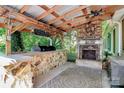 Outdoor patio with stone fireplace, stone bar, grill, and wooded views at 3311 Camden Rd, Marshville, NC 28103