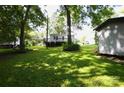 Expansive backyard with mature trees, featuring a deck, outbuilding, and lush lawn at 438 Faith Sw Dr, Concord, NC 28027