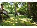 Lush backyard features a deck with stairs and a vintage outbuilding nestled among mature trees at 438 Faith Sw Dr, Concord, NC 28027