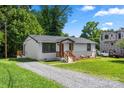 Landscaped ranch-style house featuring a gravel driveway, a new construction property, and mature shade trees at 517 Dutch Ave, Mount Holly, NC 28120