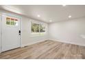 Bright living room featuring wood-look floors, a window, white walls, recessed lighting, and a front door at 517 Dutch Ave, Mount Holly, NC 28120