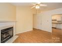 Cozy living room featuring a fireplace, wood floors, and neutral-colored walls that lead into the kitchen at 828 Saint Andrews Pl, Concord, NC 28025