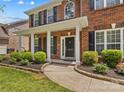 Inviting front porch and entrance with professional landscaping featuring lush plants and classic brick and black color scheme at 1011 Wadsworth Ln, Indian Trail, NC 28079