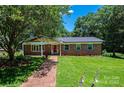Well-maintained brick home with lush lawn, brick walkway, and mature trees offering ample shade at 1036 11Th Street Circle Nw Dr, Hickory, NC 28601