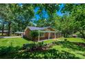 Beautifully landscaped brick home with lush green lawn, flowering plants, and mature shade trees at 1036 11Th Street Circle Nw Dr, Hickory, NC 28601