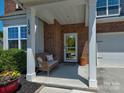 Inviting front porch with stylish wicker seating, potted plants, and a decorative wreath adorning the front door at 1324 Mona Vale Dr, Huntersville, NC 28078