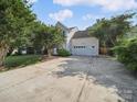 Long driveway leading to a two-car garage with well-manicured landscaping around the house at 16411 Greybriar Forest Ln, Charlotte, NC 28278