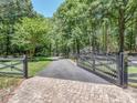Gated driveway leading to a private estate surrounded by lush greenery and mature trees at 202 Walden Ln, Weddington, NC 28104