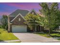 Beautiful two-story home featuring a stone and brick facade, three-car garage, and well-manicured lawn at 2100 Goddard Way, Waxhaw, NC 28173