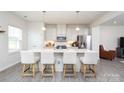 Well-lit kitchen showcases white cabinets, an island with seating, pendant lights, and stainless steel appliances at 411 Lahinch Dr, Tega Cay, SC 29708