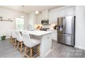 Bright kitchen featuring white cabinets, stainless steel appliances, a large island with seating and modern pendant lighting at 411 Lahinch Dr, Tega Cay, SC 29708