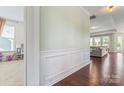 Hallway showcasing hardwood floors, decorative wainscoting, and a glimpse into the living space at 9547 Horsebit Ln, Concord, NC 28027