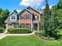 Inviting brick home with black shutters and lush front yard landscaping, offering great curb appeal at 9800 Ashley Farm Dr, Matthews, NC 28105