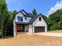 New construction two-story home featuring white siding, black trim, a two-car garage, and a charming front porch at 135 Brookview Dr, Shelby, NC 28152
