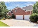 Spacious three-car garage with ample driveway space, set against a lush green backdrop at 13824 Glen Abbey Dr, Charlotte, NC 28278
