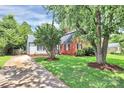 Lovely exterior view of a property featuring a red brick house and white siding, surrounded by green lawn and trees at 3909 Woodbriar Trl, Charlotte, NC 28205