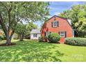 A charming two-story home has a red brick exterior, a well-maintained lawn, and mature trees at 3909 Woodbriar Trl, Charlotte, NC 28205