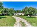 Charming single-story home with a long gravel driveway and spacious front yard with mature trees at 4905 Grassy Creek Rd, Denver, NC 28037