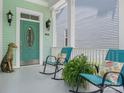 Inviting front porch with rocking chairs, a decorative dog statue, and a welcoming oval-windowed front door at 8918 Cotton Press Rd, Charlotte, NC 28277