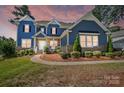 Charming two-story home featuring a covered porch, manicured landscaping, and a beautiful blue exterior at 101 Cross Current Ln, Belmont, NC 28012