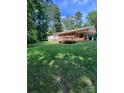 Large backyard with wooden deck, covered porch, and a lush green lawn surrounded by trees at 2300 Lakeview Cir # 10, Matthews, NC 28105