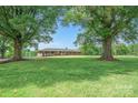 Inviting brick home framed by mature trees and a lush green lawn at 14411 Eastfield Rd, Huntersville, NC 28078