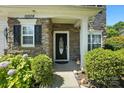 Inviting front entrance with stone accents, decorative shrubbery, and a stylish front door, showcasing curb appeal at 15508 Normans Landing Dr, Charlotte, NC 28273