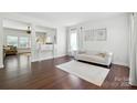 Bright living room featuring hardwood floors, a white couch, and a neutral rug creating a welcoming space at 15508 Normans Landing Dr, Charlotte, NC 28273