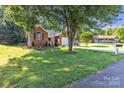 Beautifully landscaped front yard with mature trees framing a brick home with an attached garage at 5476 Twelve Oak Ln, Conover, NC 28613