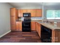 Open kitchen with wood cabinetry, black appliances, and stainless steel sink at 7315 Fig Ln, Charlotte, NC 28215