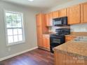 Bright kitchen featuring wood cabinets, black appliances, and laminate floors at 7315 Fig Ln, Charlotte, NC 28215