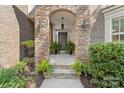 Inviting front door framed by a stone archway, decorative plants, and outdoor lighting at 10320 Lemington Dr, Mint Hill, NC 28227