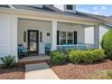 Inviting front porch with rocking chairs and bench seating, complemented by a black front door and landscaped yard at 1103 Phar Lap Dr, Indian Trail, NC 28079