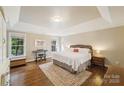 Spacious bedroom featuring hardwood floors, tray ceiling, windows, and a neutral color palette at 1237 Saint Johns Ave, Matthews, NC 28104